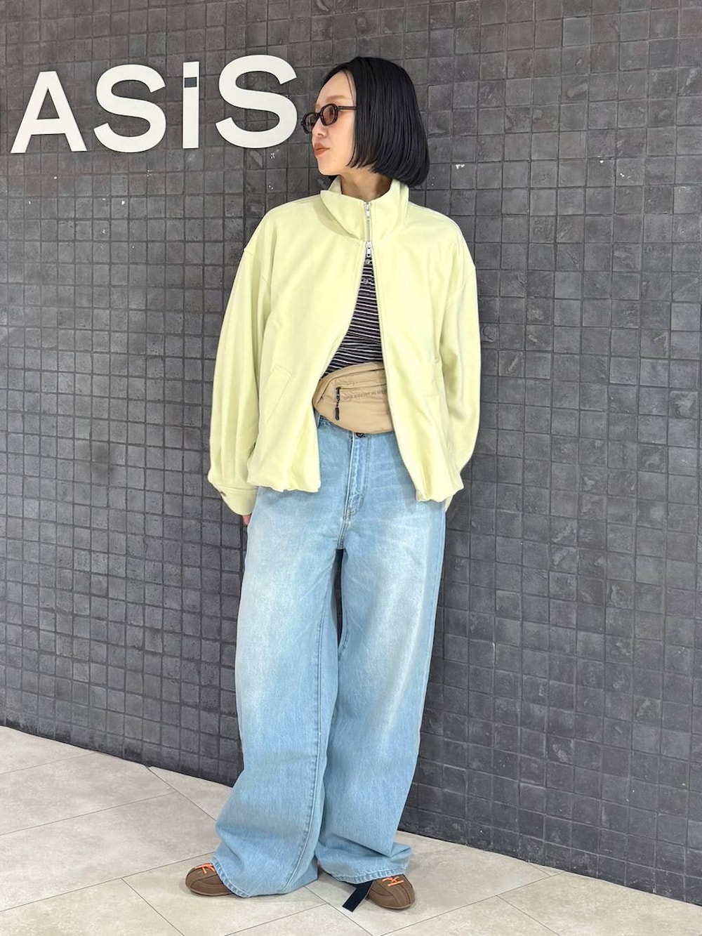 ブラウン系のTシャツ/カットソー、ブラウン系のスニーカー、ブルー系のデニムパンツを着用したレディースの春コーディネートの2枚目の写真