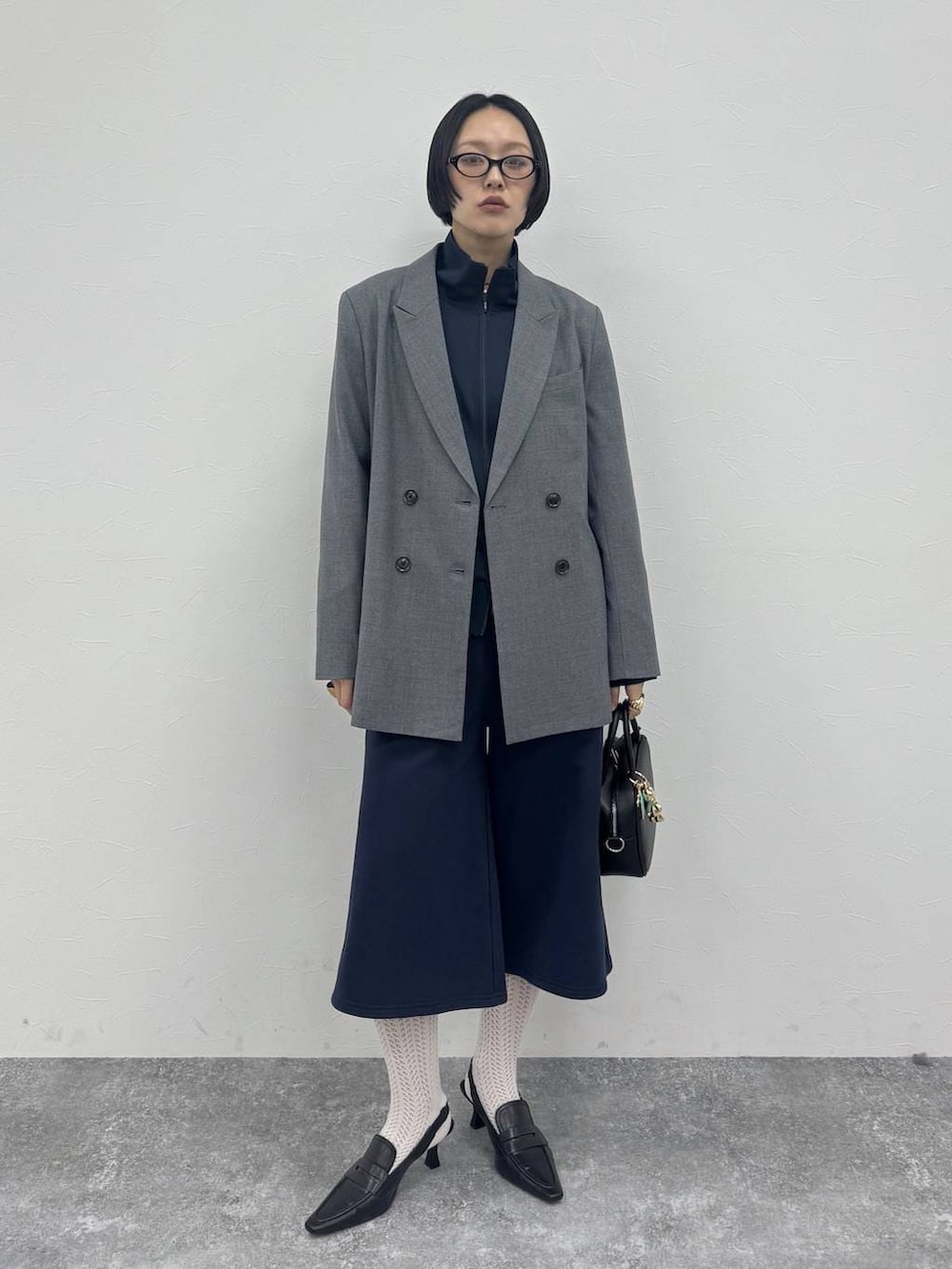 ブラック系のローファー、ブラック系のショルダーバッグ、グレー系のテーラードジャケットを着用したレディースの冬コーディネートの6枚目の写真