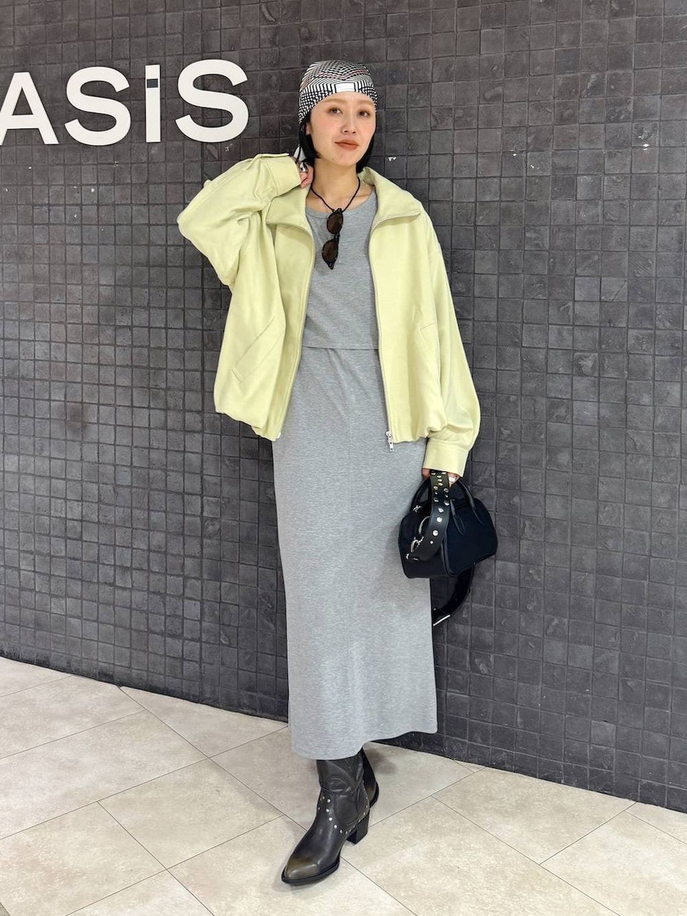 ブラック系のボストンバッグ、ブラック系のブーツ、グレー系のワンピースを着用したレディースの春コーディネートの2枚目の写真