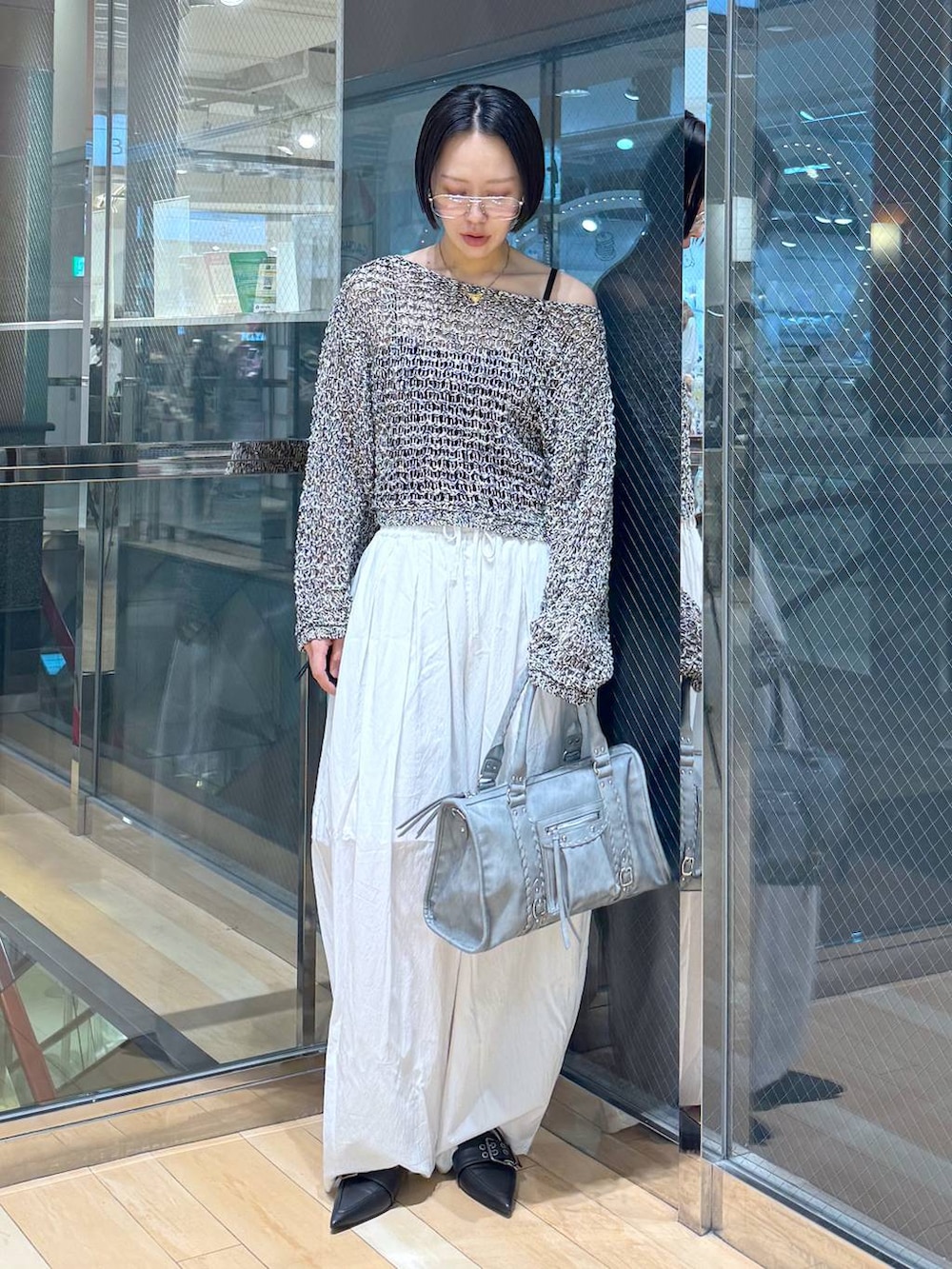 ブラック系のパンプス、ブルー系のボストンバッグ、ブラック系のニット/セーターを着用したレディースの春コーディネートの2枚目の写真