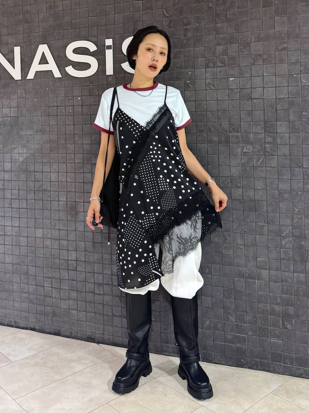 ブラック系のチュニック、ベージュ系のスウェットパンツ、ブラック系のブーツを着用したレディースの夏コーディネートの3枚目の写真