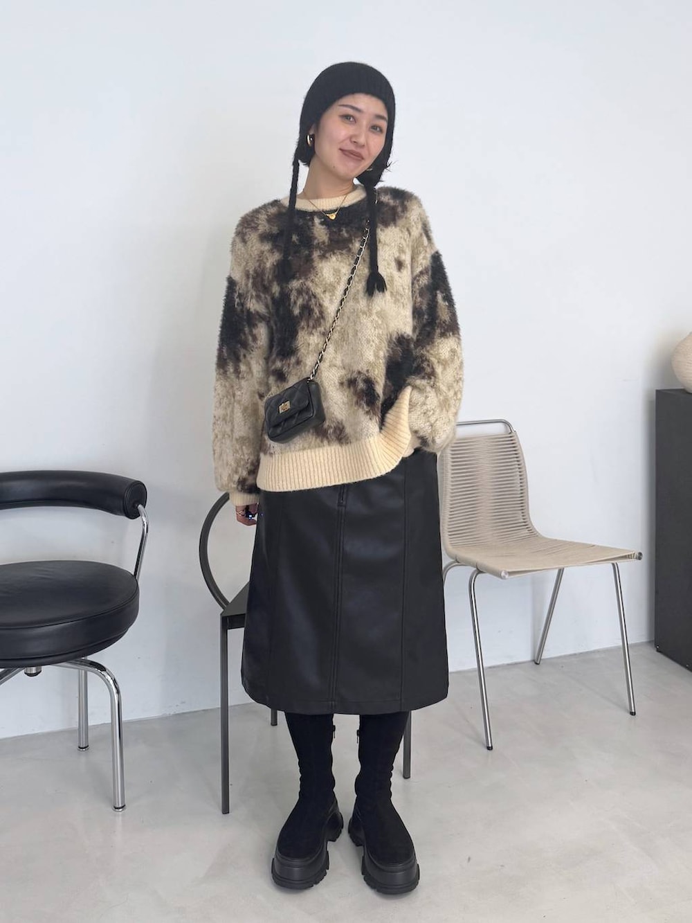 ブラウン系のニット/セーター、ブラック系のブーツ、ブラック系のスカートを着用したレディースの秋コーディネートの4枚目の写真