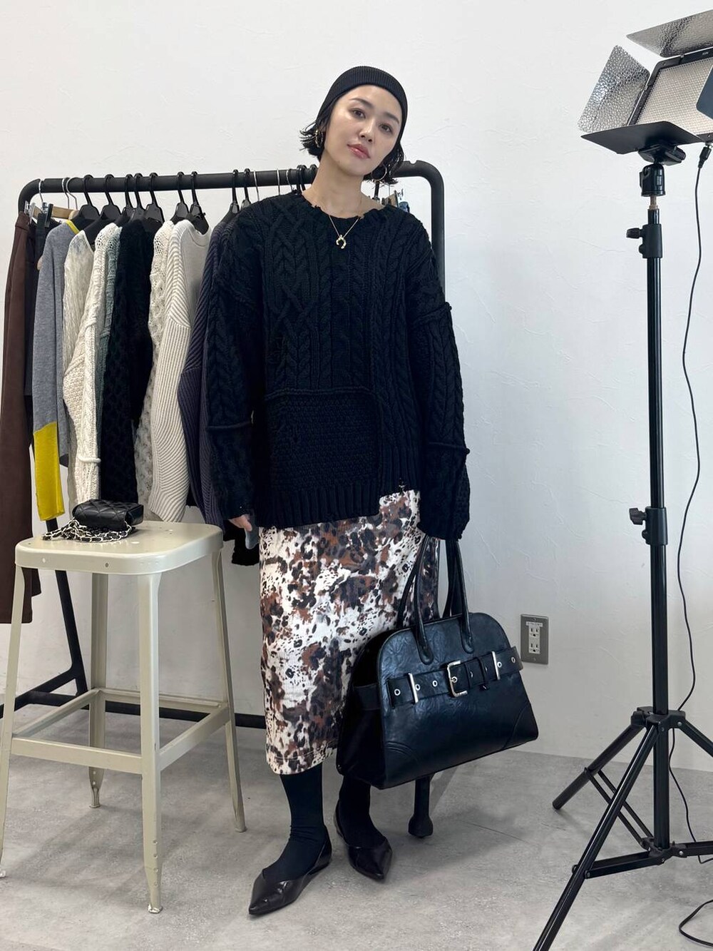 ベージュ系のスカート、ブラック系のショルダーバッグ、ブラック系のニット/セーターを着用したレディースの秋コーディネートの2枚目の写真