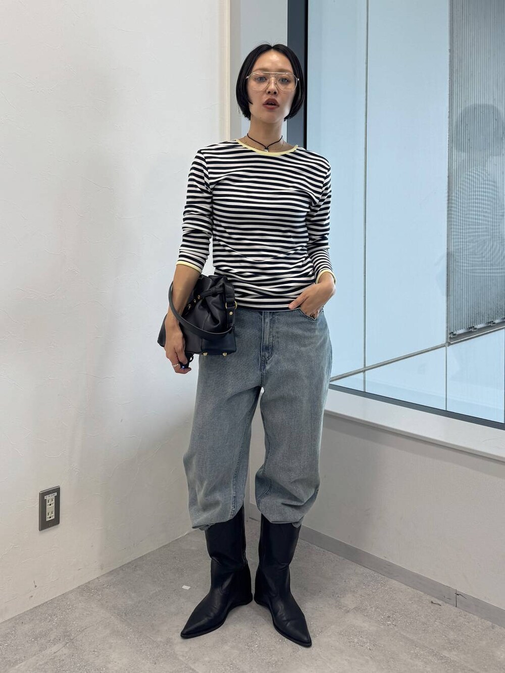 ブルー系のデニムパンツ、ブラック系のショルダーバッグ、ブラック系のブーツを着用したレディースの夏コーディネートの4枚目の写真