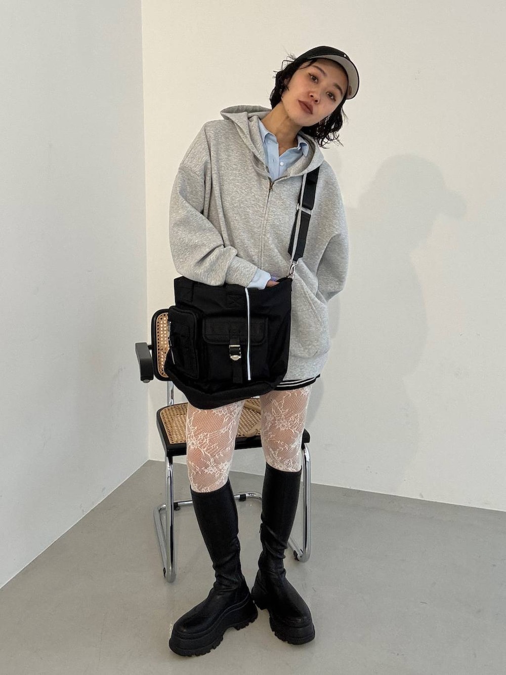 ブラック系のブーツ、ブラック系のトートバッグ、グレー系のパーカーを着用したレディースの冬コーディネートの3枚目の写真