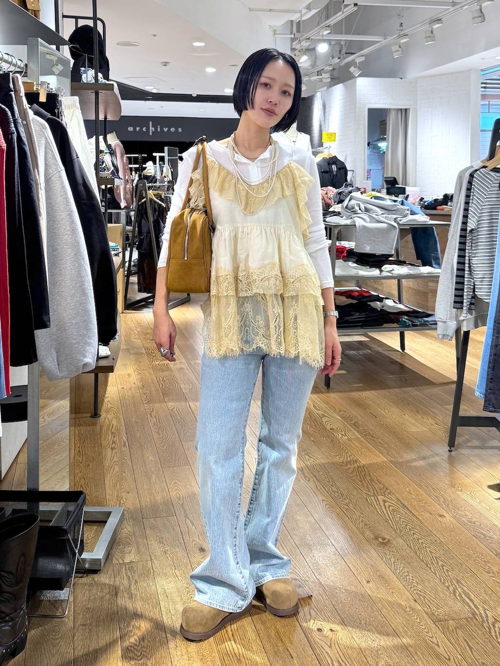 ホワイト系のTシャツ/カットソー、ブラウン系のボストンバッグ、ベージュ系のモカシン/デッキシューズを着用したレディースの春コーディネートの2枚目の写真