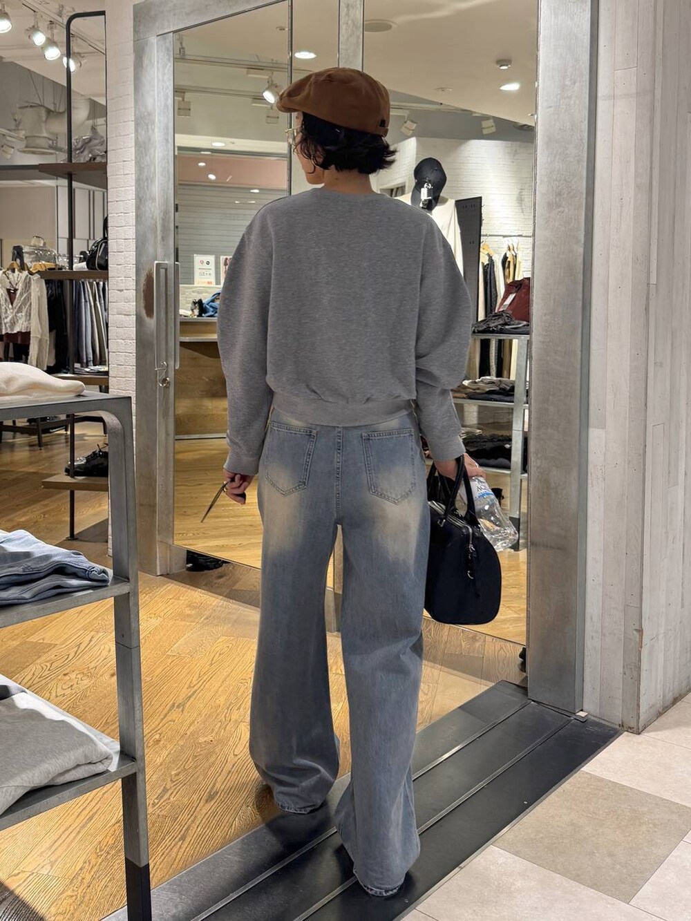 グリーン系のボストンバッグ、ブルー系のデニムパンツ、ブラック系のブーツを着用したレディースの秋コーディネートの4枚目の写真