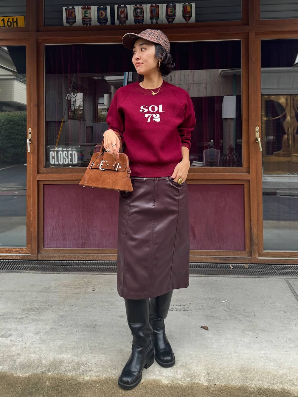 ブラウン系のボストンバッグ、ブラウン系のスカート、レッド系のニット/セーターを着用したレディースの秋コーディネートの4枚目の写真