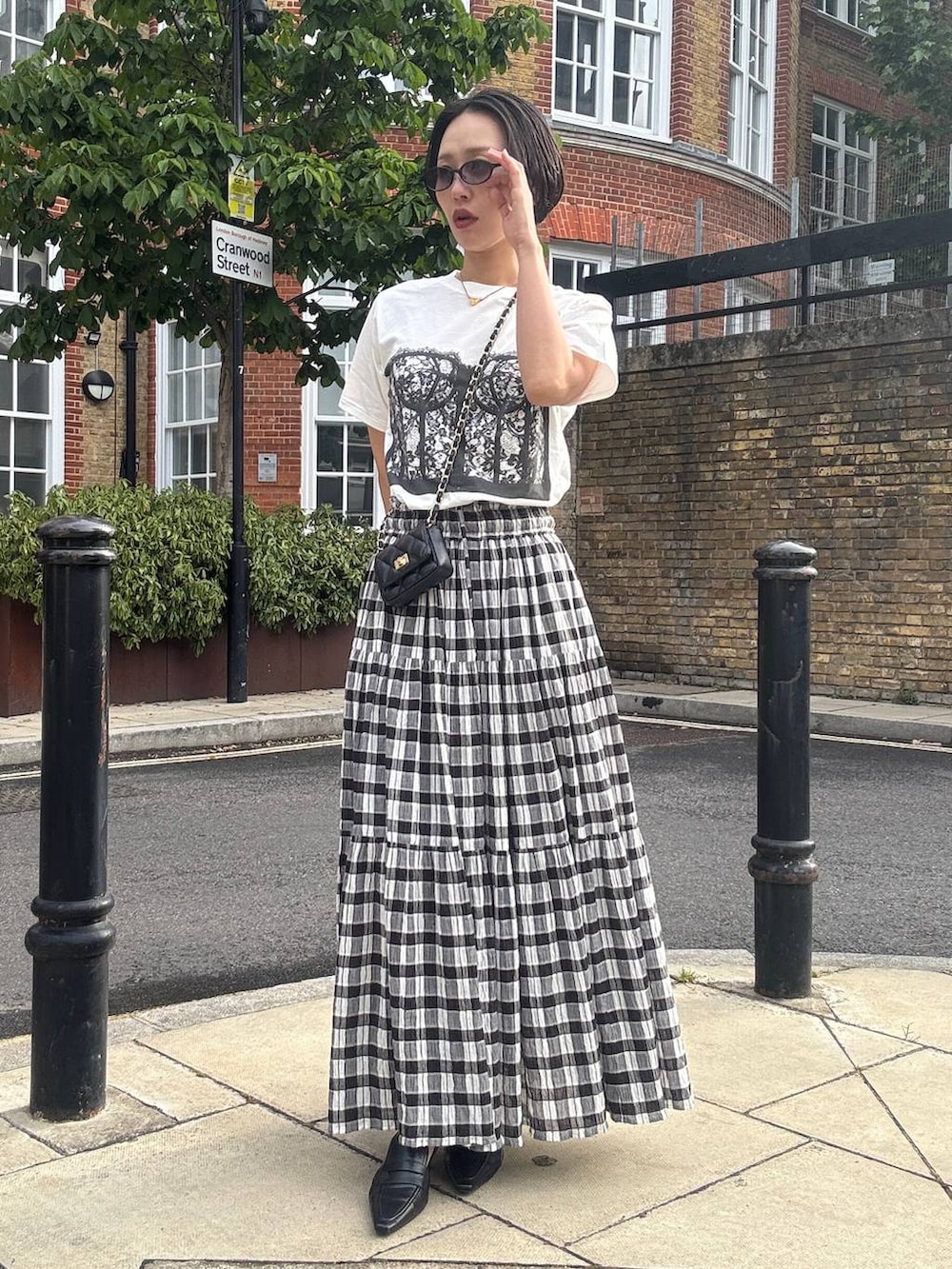 ブラック系のスカート、ホワイト系のTシャツ/カットソー、ブラック系のサングラスを着用したレディースの夏コーディネートの5枚目の写真