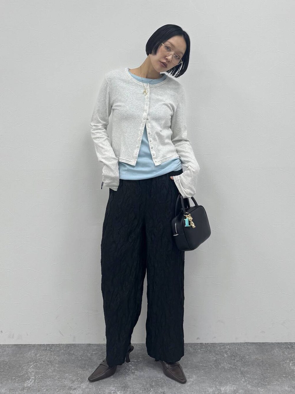 ブラウン系のローファー、ブラック系のショルダーバッグを着用したレディースの冬コーディネートの2枚目の写真