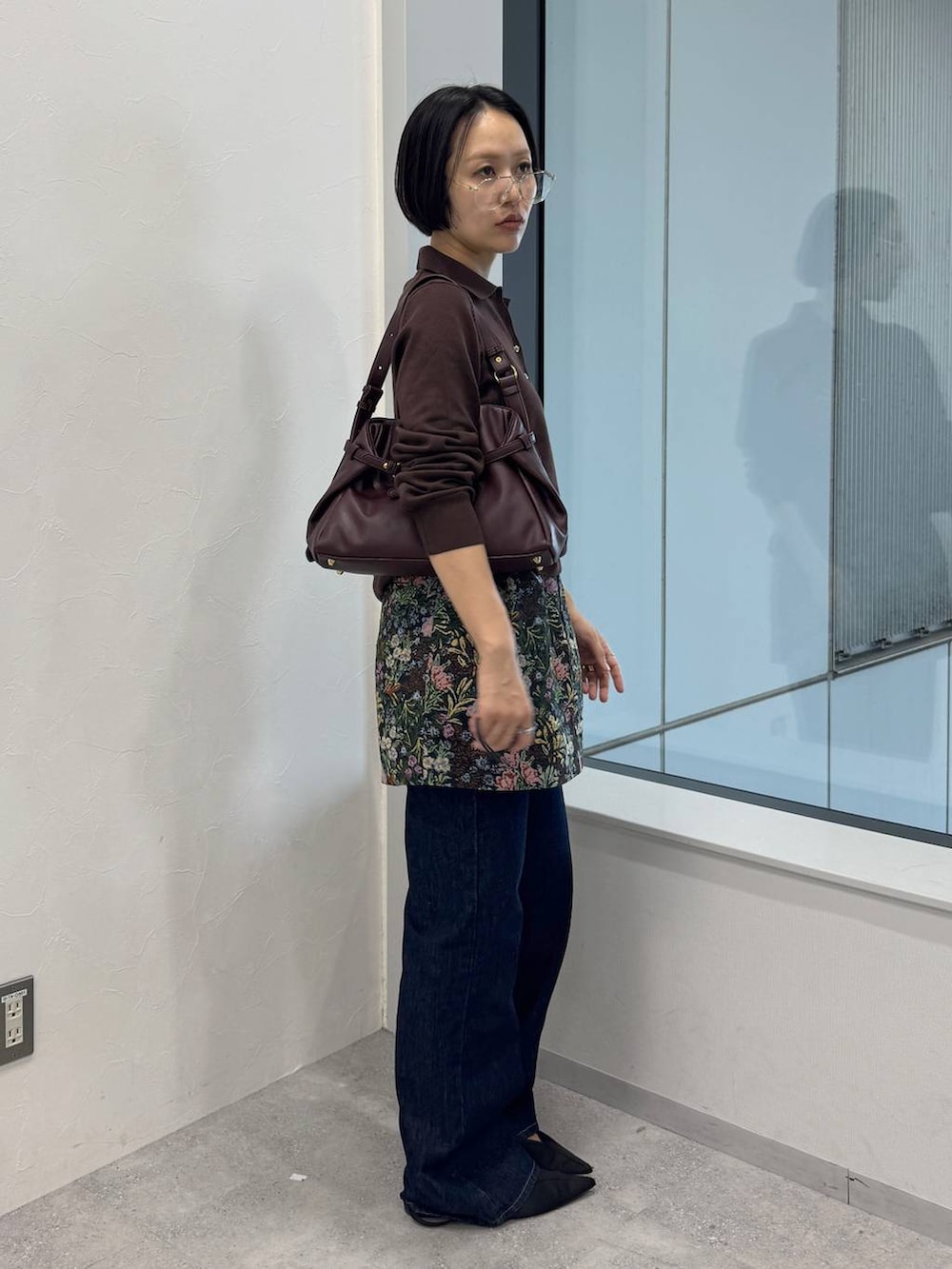 レッド系のショルダーバッグ、ブルー系のデニムパンツ、ブラック系のスカートを着用したレディースの夏コーディネートの2枚目の写真