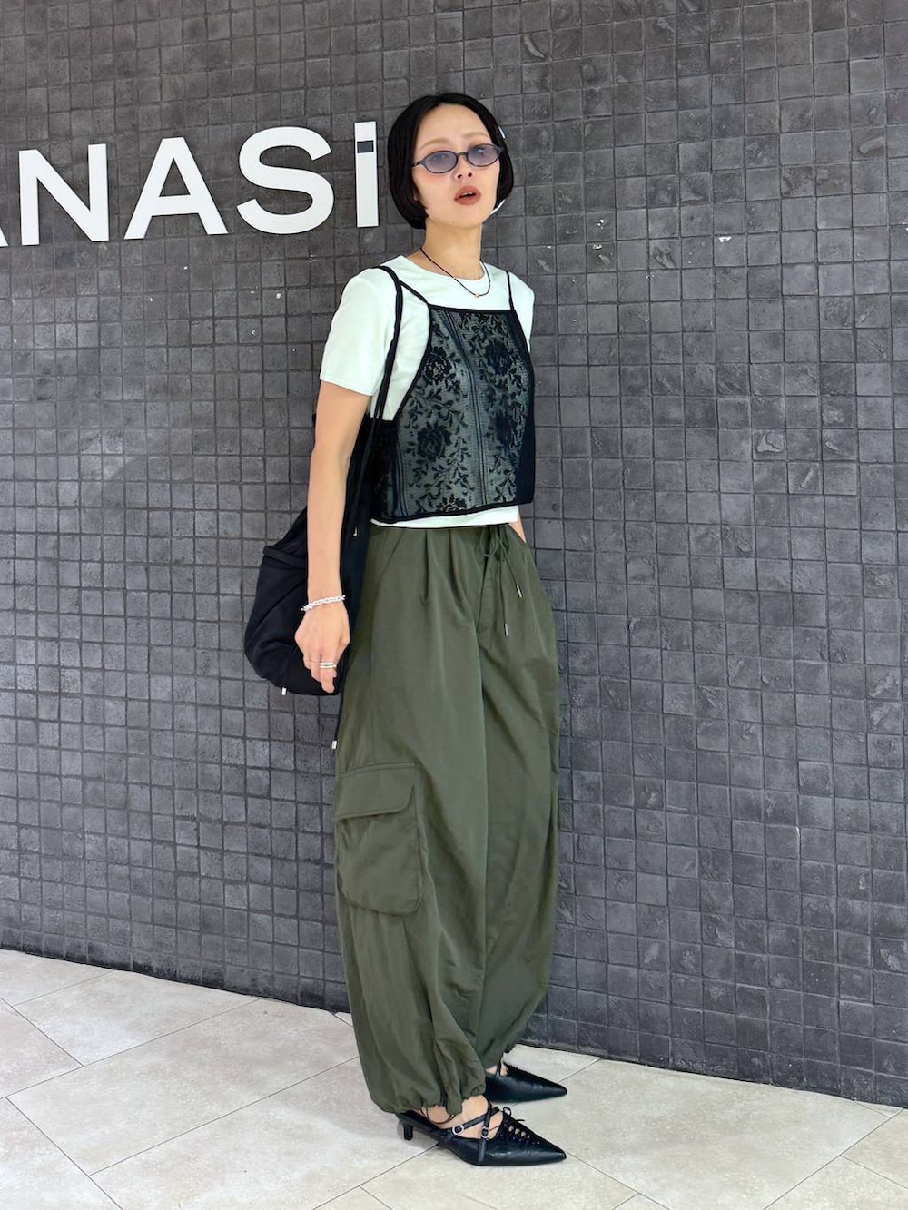 ブラック系のパンプス、グリーン系のTシャツ/カットソー、ブラック系のサングラスを着用したレディースの夏コーディネートの2枚目の写真