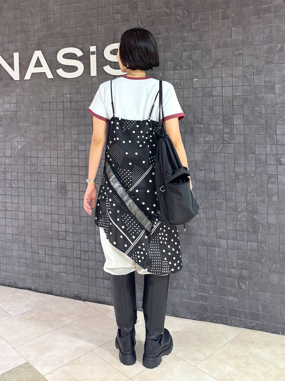 ブラック系のチュニック、ベージュ系のスウェットパンツ、ブラック系のブーツを着用したレディースの夏コーディネートの2枚目の写真