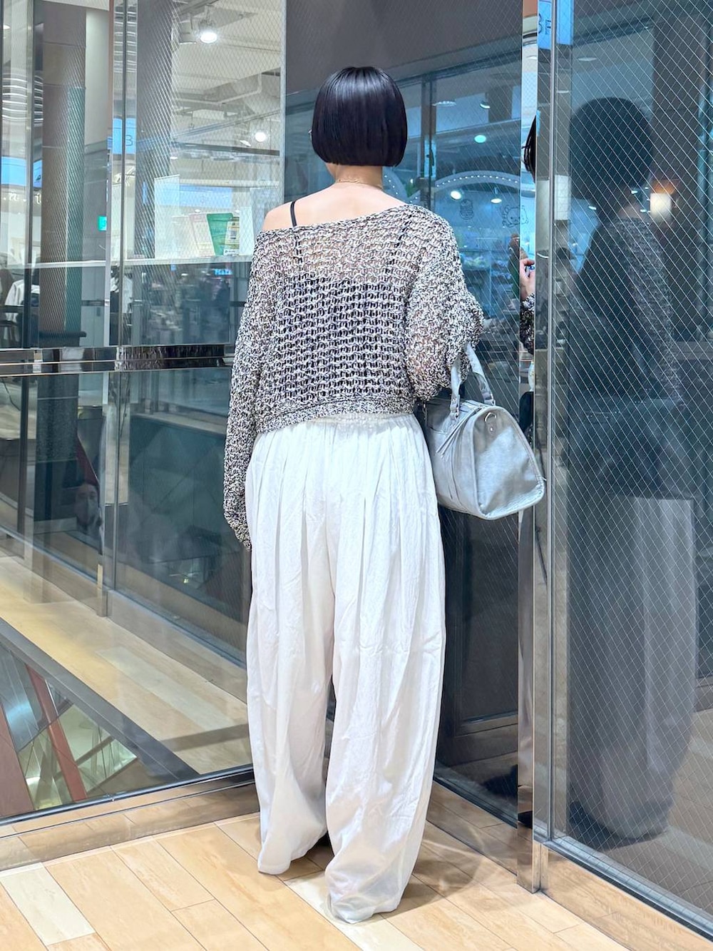 ブラック系のパンプス、ブルー系のボストンバッグ、ブラック系のニット/セーターを着用したレディースの春コーディネートの4枚目の写真