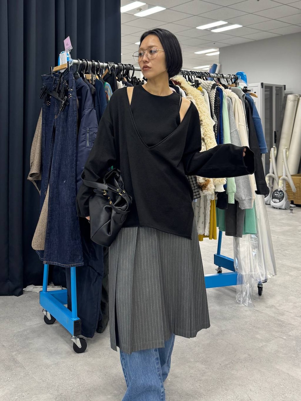 ブラック系のショルダーバッグ、ブルー系のデニムパンツ、ブラック系のパンプスを着用したレディースの夏コーディネートの2枚目の写真