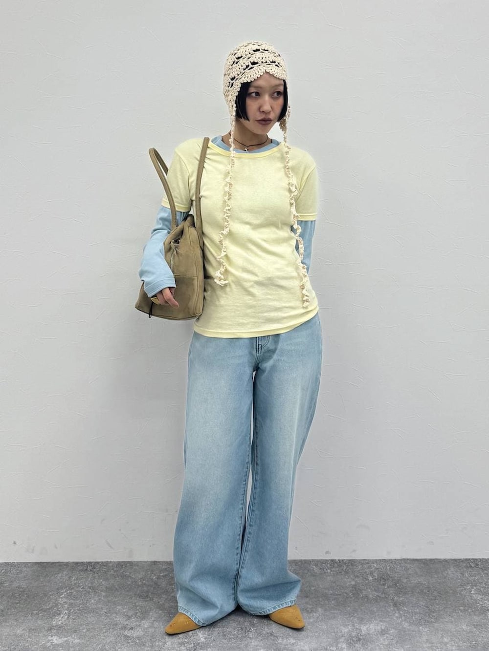 ベージュ系のショルダーバッグ、ベージュ系のパンプス、ブルー系のデニムパンツを着用したレディースの冬コーディネートの3枚目の写真