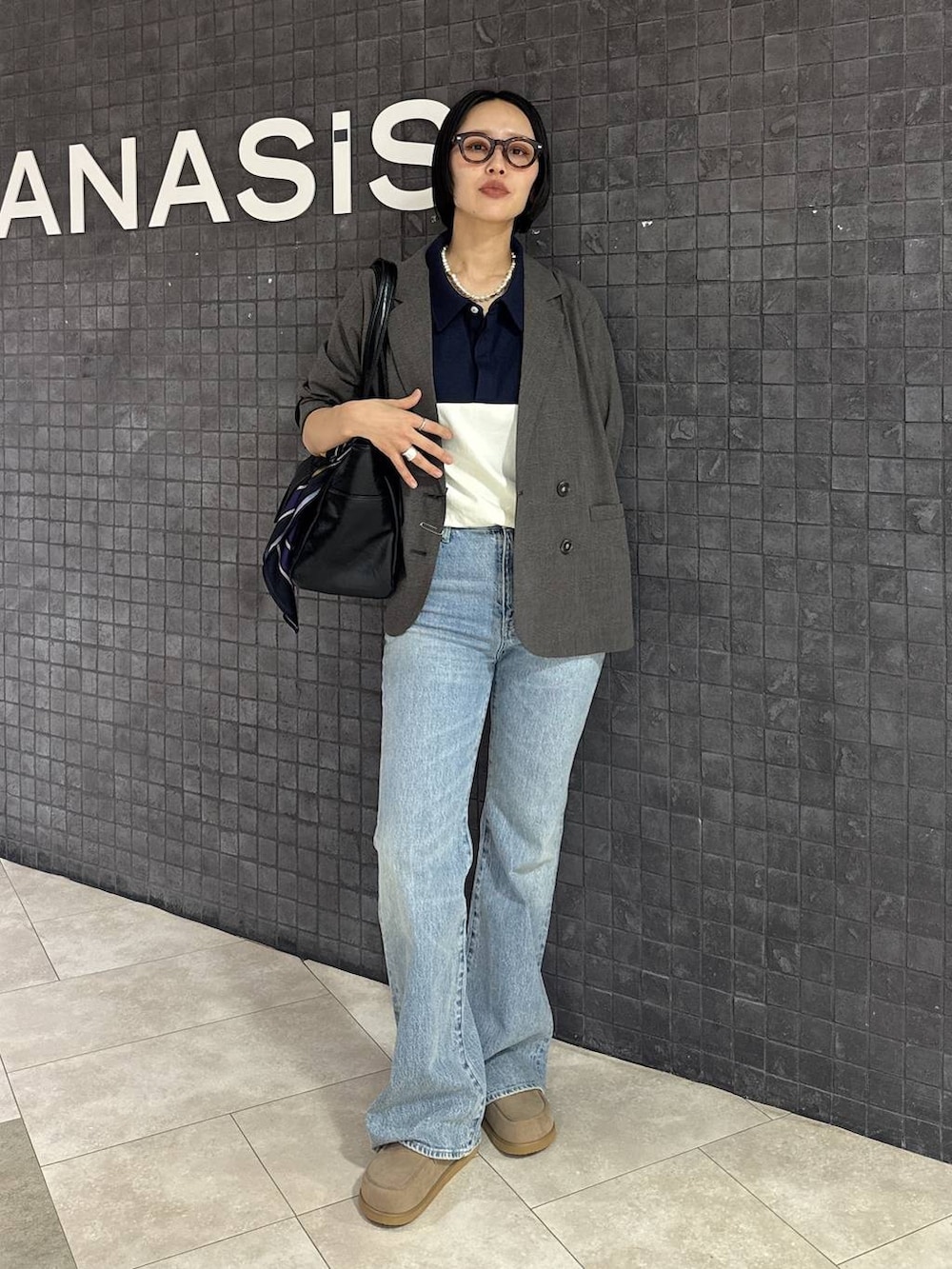 ブルー系のデニムパンツ、ベージュ系のローファー、ブラック系のトートバッグを着用したレディースの春コーディネートの2枚目の写真