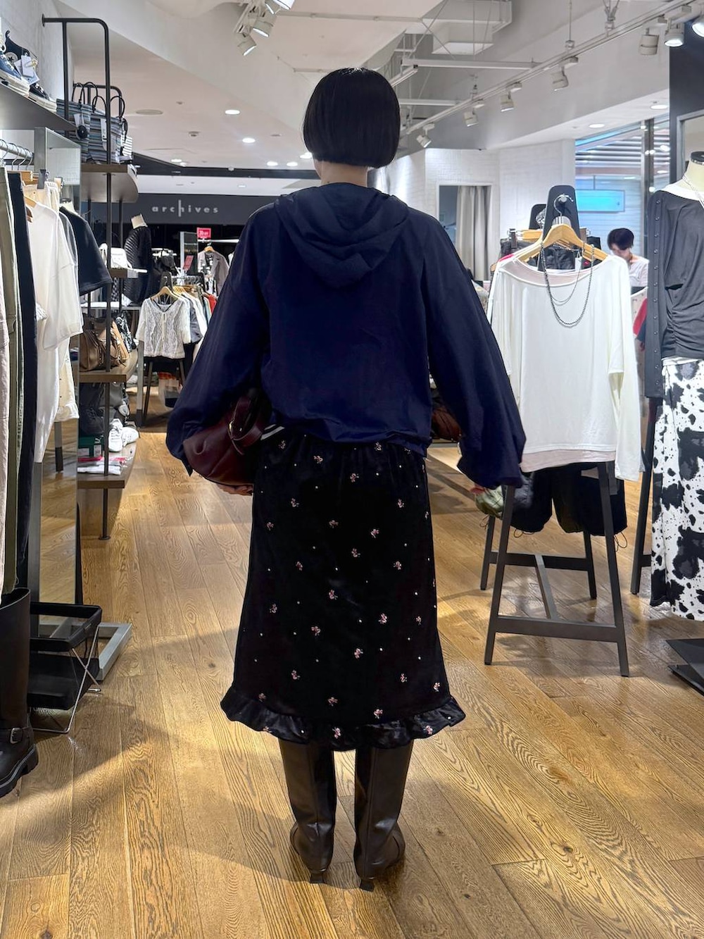 ブラック系のブーツ、ブラック系のスカート、レッド系のショルダーバッグを着用したレディースの夏コーディネートの3枚目の写真