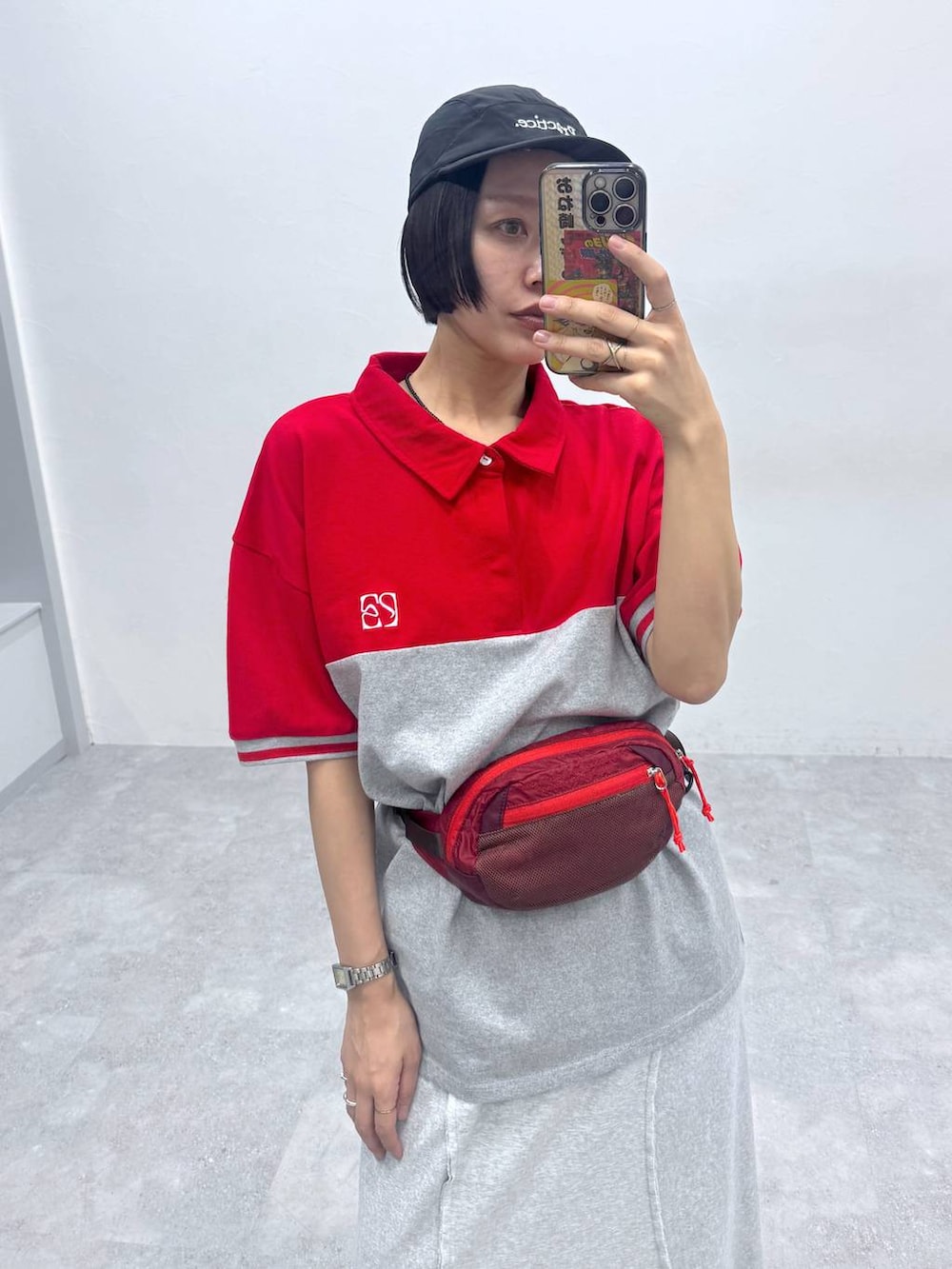 グレー系のスカート、レッド系のポロシャツを着用したレディースの春コーディネートの3枚目の写真