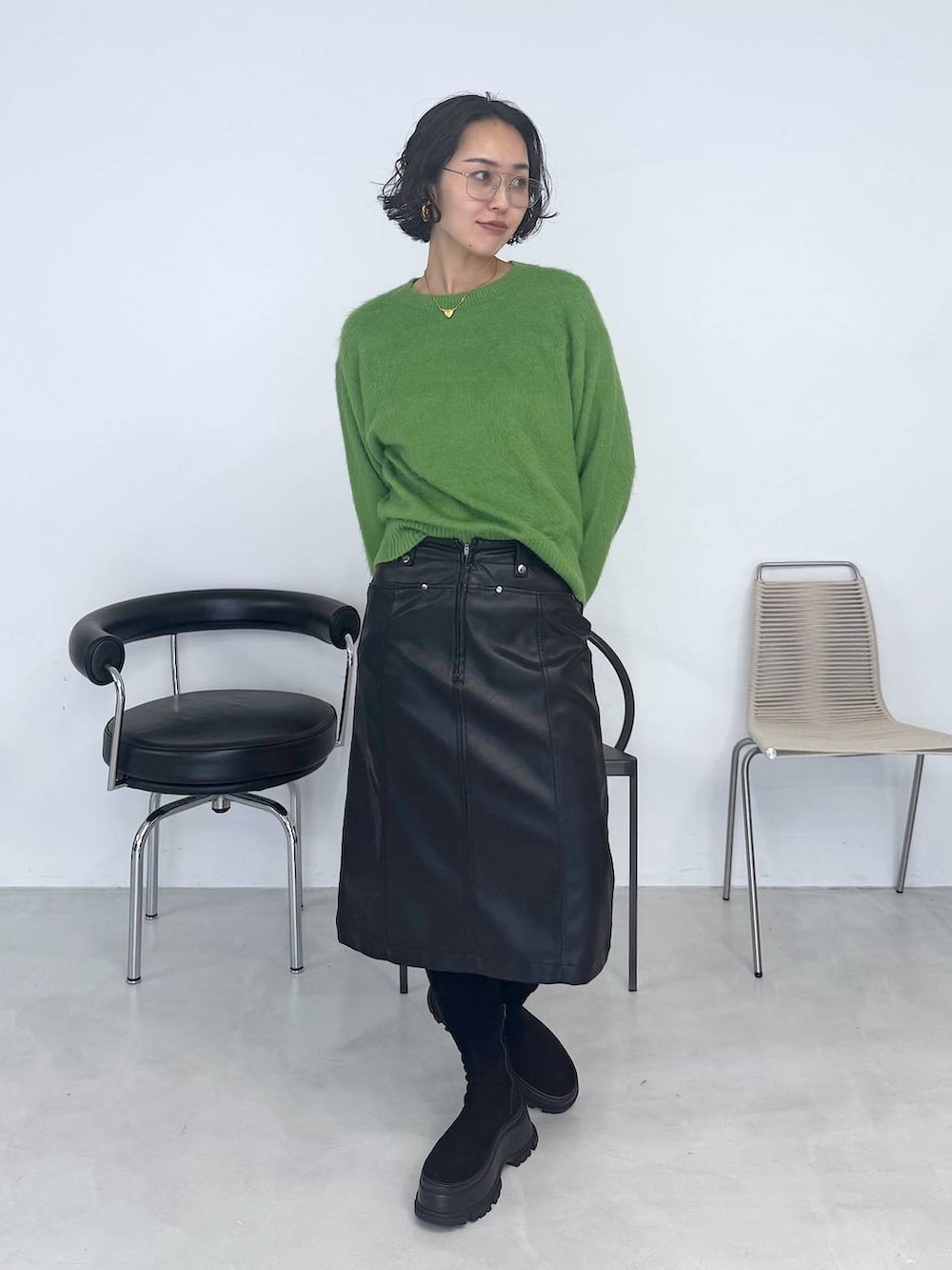 ブラック系のブーツ、グリーン系のニット/セーター、ブラック系のスカートを着用したレディースの秋コーディネートの4枚目の写真
