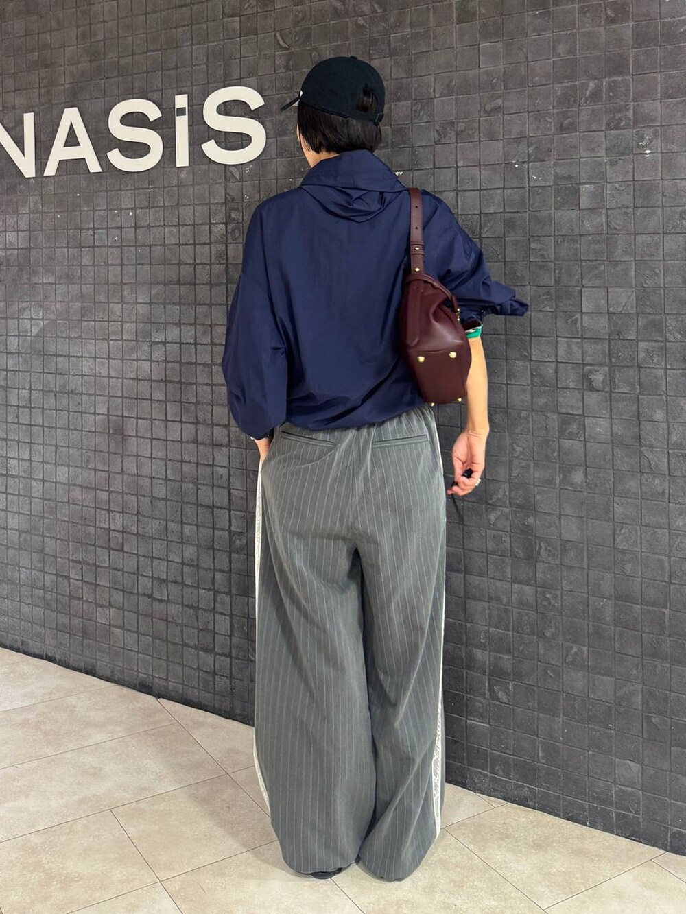 グレー系のスラックス、レッド系のショルダーバッグ、ブラック系のサンダルを着用したレディースの夏コーディネートの3枚目の写真