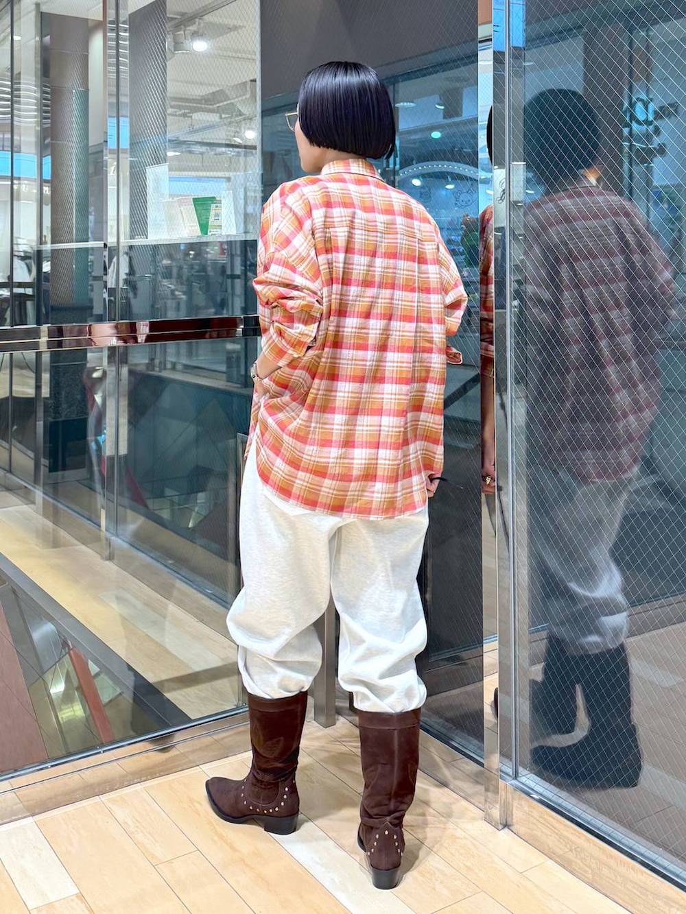 ブラウン系のブーツ、ホワイト系のデニムパンツ、レッド系のタンクトップを着用したレディースの春コーディネートの4枚目の写真