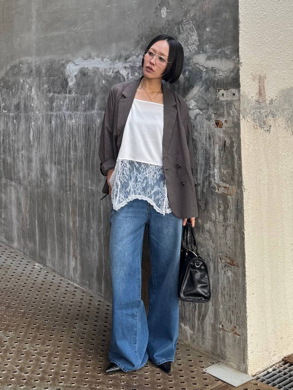 ブラック系のボストンバッグ、ブルー系のデニムパンツ、ブラウン系のテーラードジャケットを着用したレディースの春コーディネートの2枚目の写真