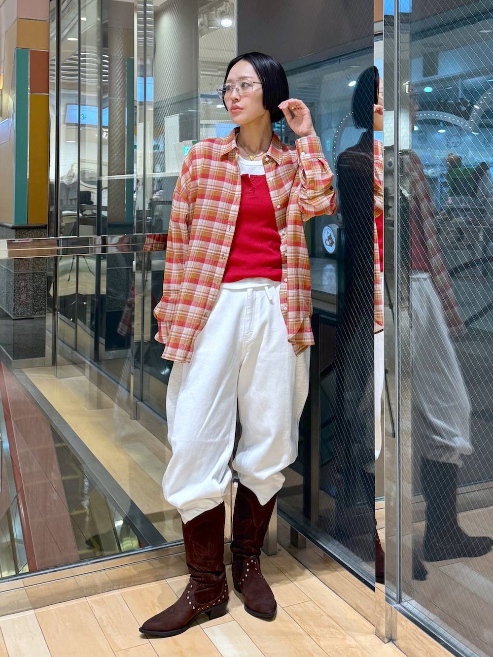 ブラウン系のブーツ、ホワイト系のデニムパンツ、レッド系のタンクトップを着用したレディースの春コーディネートの2枚目の写真