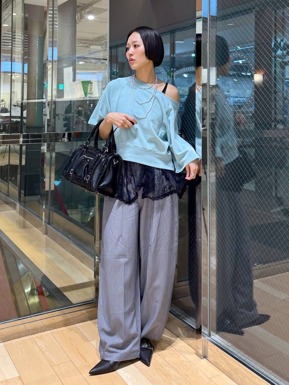 ブラック系のパンプス、ブラック系のボストンバッグ、グレー系のスラックスを着用したレディースの春コーディネートの6枚目の写真