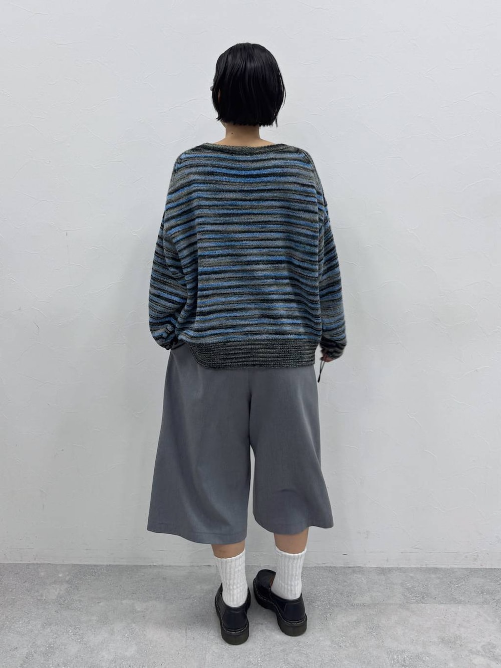 グレー系のスラックス、ブルー系のニット/セーターを着用したレディースの秋コーディネートの4枚目の写真
