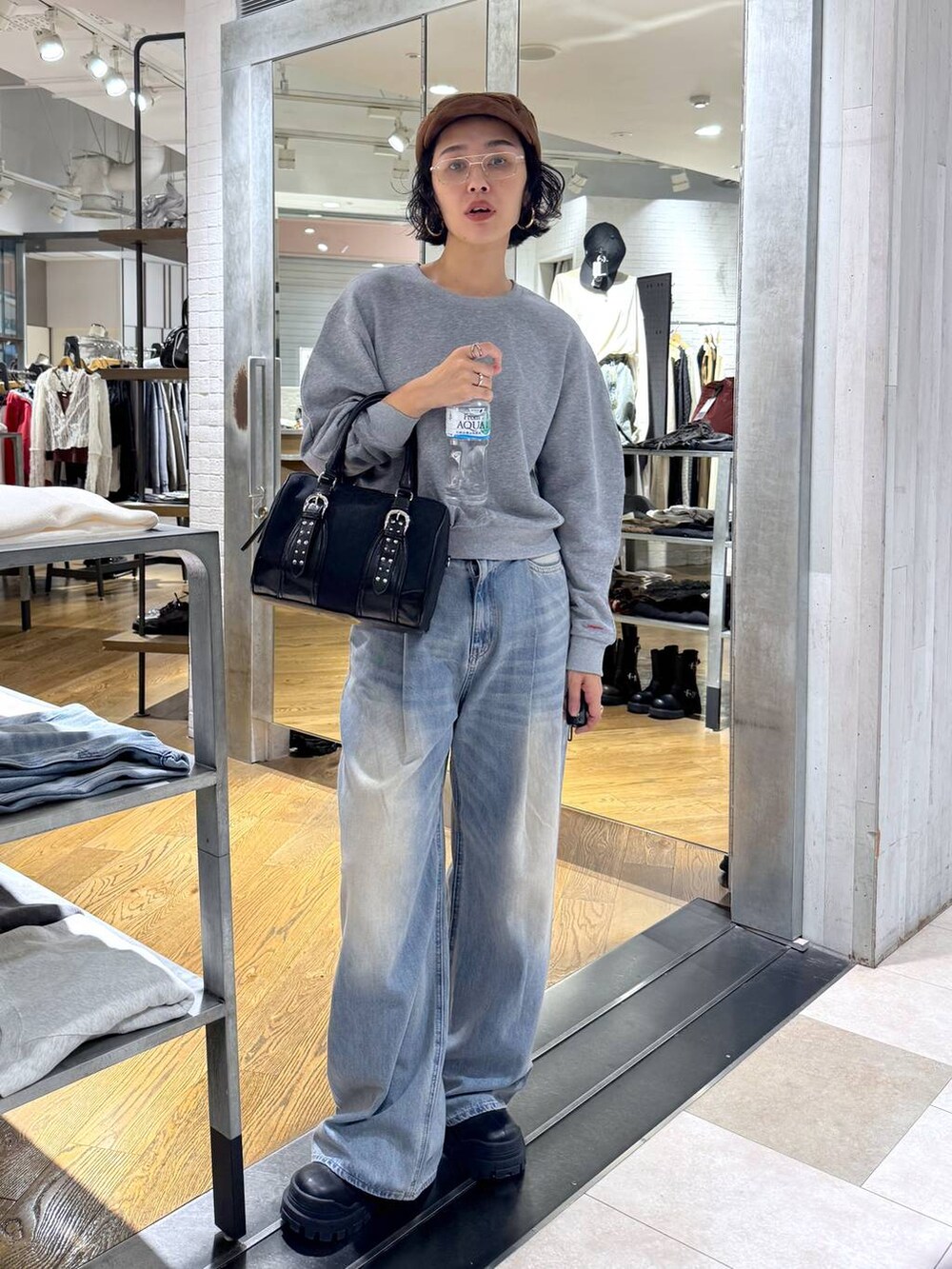 グリーン系のボストンバッグ、ブルー系のデニムパンツ、ブラック系のブーツを着用したレディースの秋コーディネートの6枚目の写真