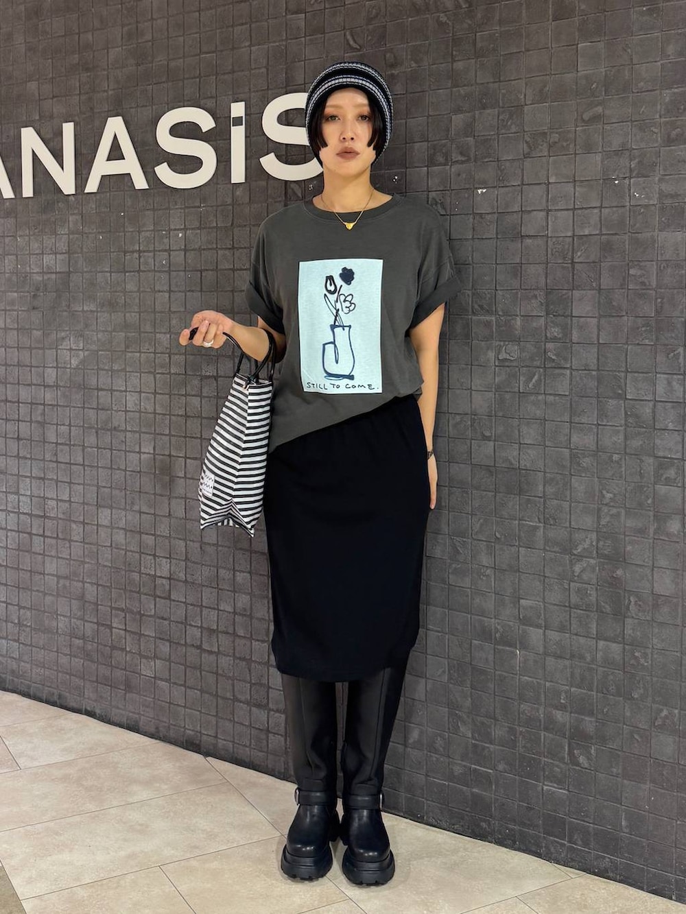 ブラック系のスカート、グレー系のTシャツ/カットソー、ブラック系のブーツを着用したレディースの夏コーディネートの4枚目の写真