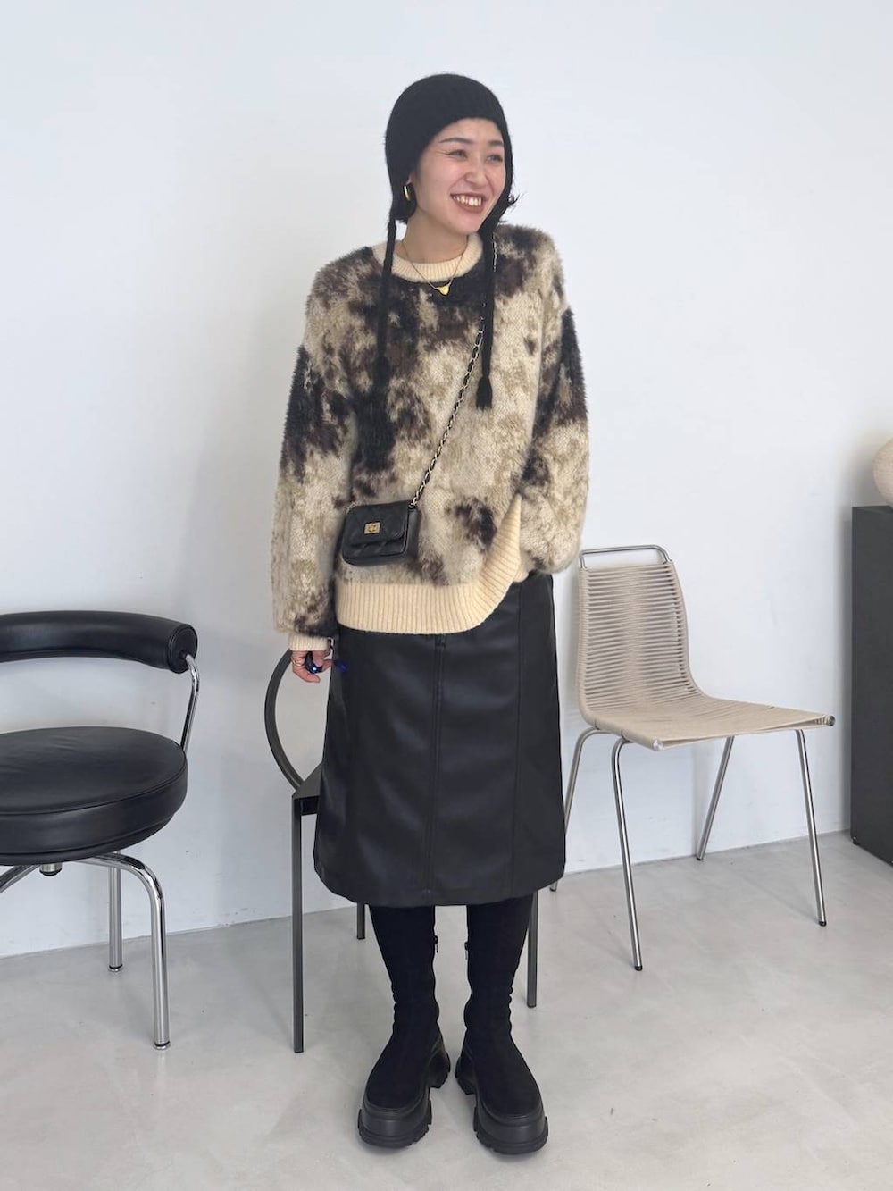 ブラウン系のニット/セーター、ブラック系のブーツ、ブラック系のスカートを着用したレディースの秋コーディネートの2枚目の写真