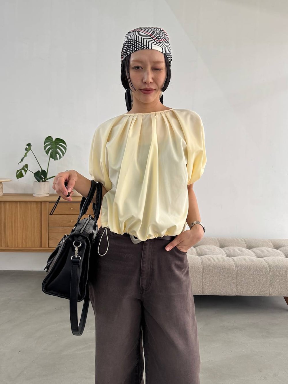 ブラック系のボストンバッグ、ブラック系のパンプス、ブラウン系のデニムパンツを着用したレディースの春コーディネートの5枚目の写真