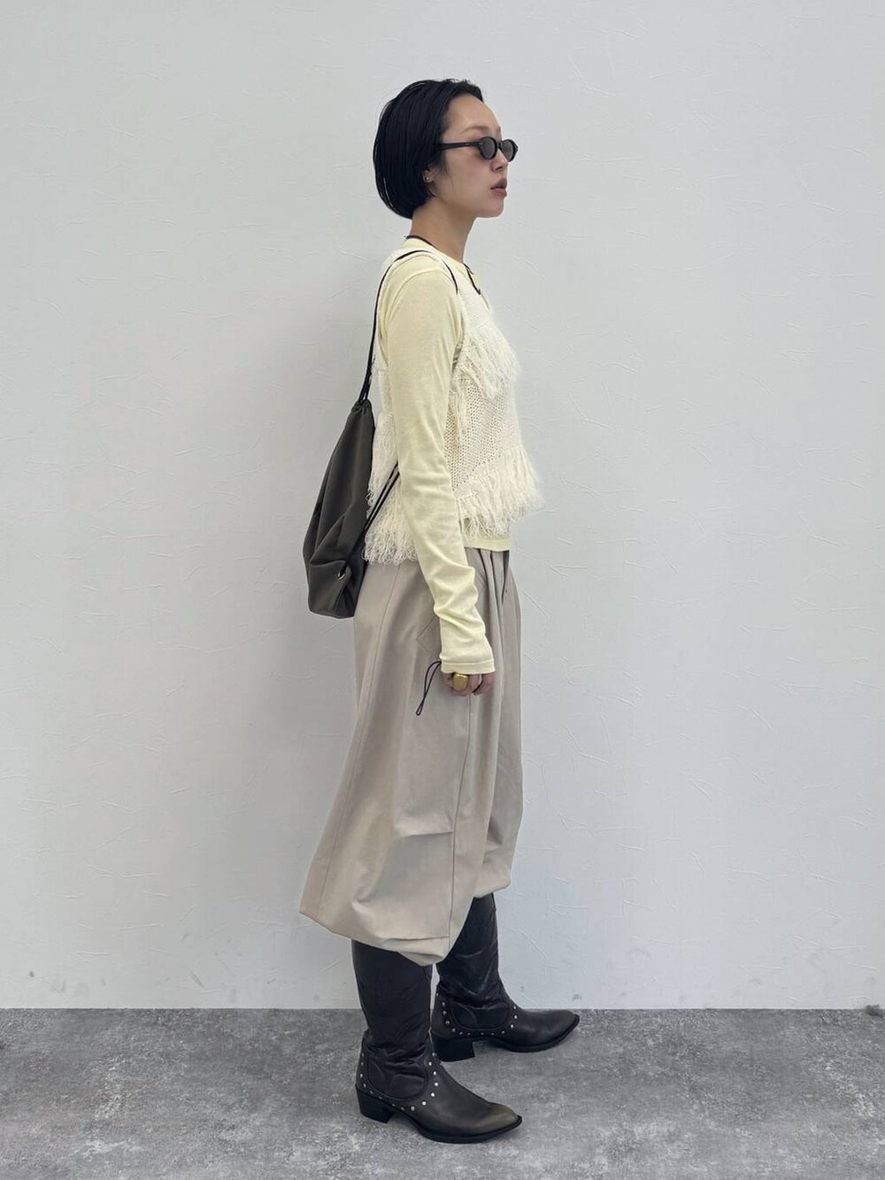 ブラック系のブーツ、イエロー系のTシャツ/カットソー、ベージュ系のその他パンツを着用したレディースの冬コーディネートの5枚目の写真