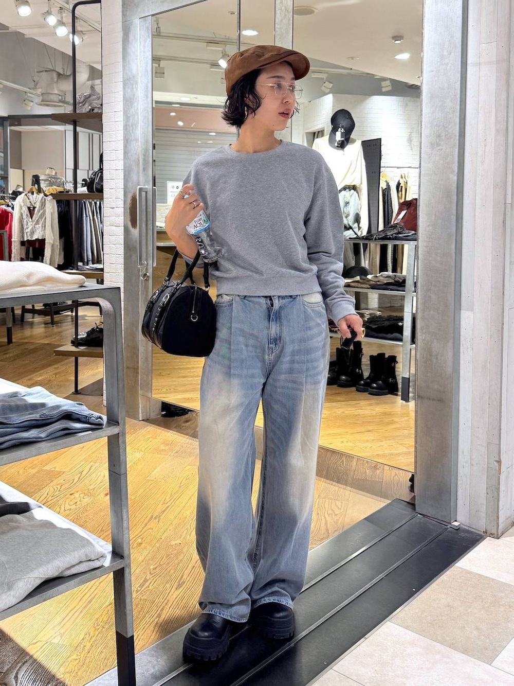 グリーン系のボストンバッグ、ブルー系のデニムパンツ、ブラック系のブーツを着用したレディースの秋コーディネートの7枚目の写真