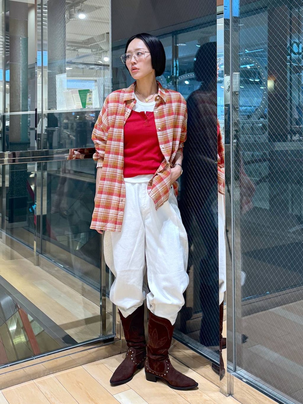 ブラウン系のブーツ、ホワイト系のデニムパンツ、レッド系のタンクトップを着用したレディースの春コーディネートの5枚目の写真