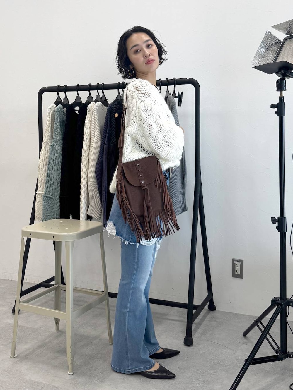 ブラウン系のショルダーバッグ、ブルー系のデニムスカート、ホワイト系のニット/セーターを着用したレディースの秋コーディネートの4枚目の写真