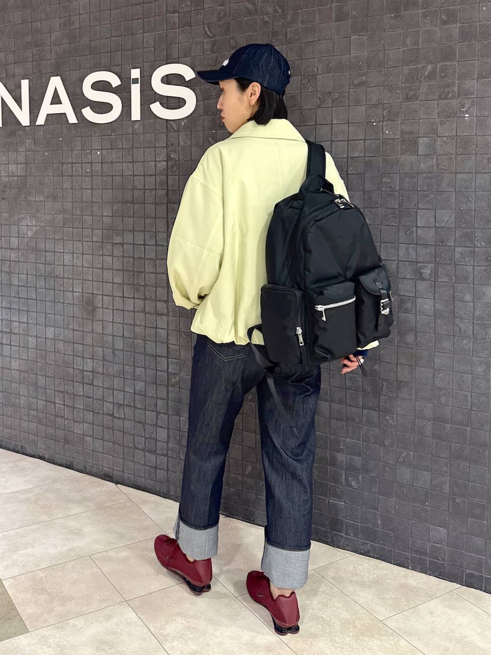 ブラック系のバックパック/リュック、ブルー系のデニムパンツ、ブルー系のポロシャツを着用したレディースの春コーディネートの2枚目の写真