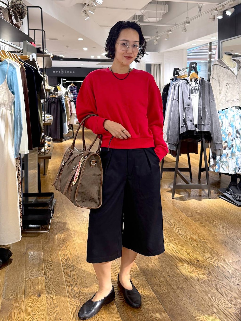 グリーン系のトートバッグ、ブラック系のその他パンツ、レッド系のスウェットを着用したレディースの秋コーディネートの6枚目の写真