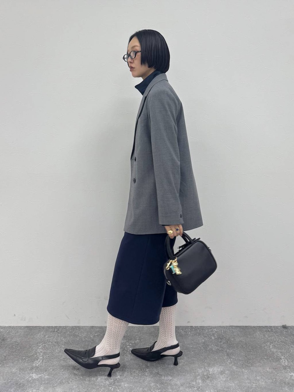 ブラック系のローファー、ブラック系のショルダーバッグ、グレー系のテーラードジャケットを着用したレディースの冬コーディネートの3枚目の写真