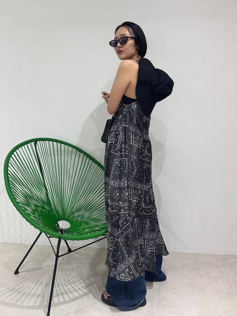 ブルー系のデニムパンツ、ブラック系のハンドバッグ、ブラック系のワンピースを着用したレディースの春コーディネートの2枚目の写真