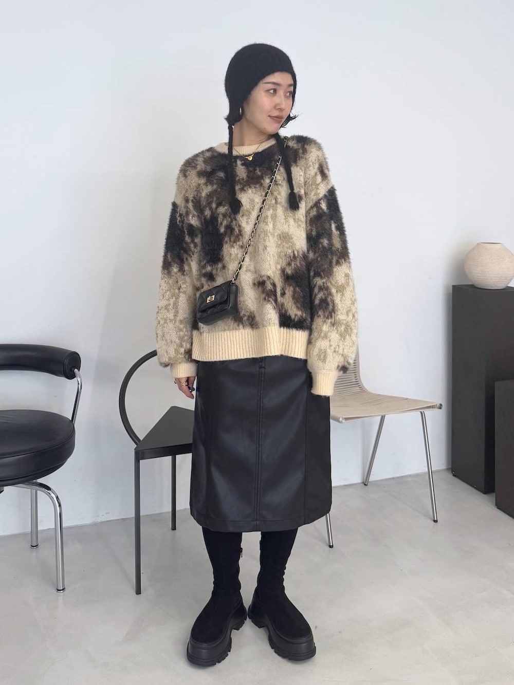 ブラウン系のニット/セーター、ブラック系のブーツ、ブラック系のスカートを着用したレディースの秋コーディネートの7枚目の写真