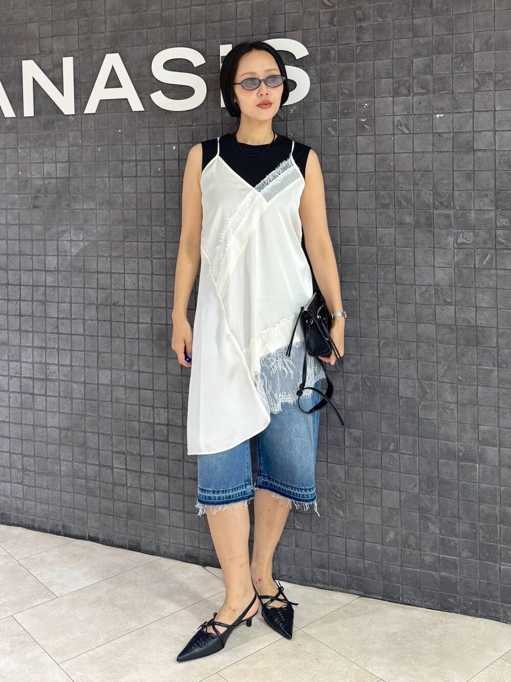 ブラック系のパンプス、ブルー系のデニムパンツ、ブラック系のTシャツ/カットソーを着用したレディースの夏コーディネートの4枚目の写真