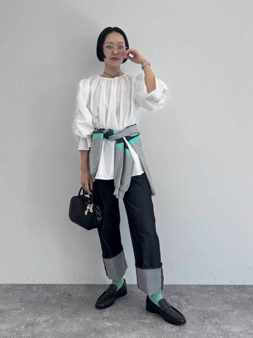 ブラック系のショルダーバッグ、ブルー系のデニムパンツを着用したレディースの冬コーディネートの5枚目の写真