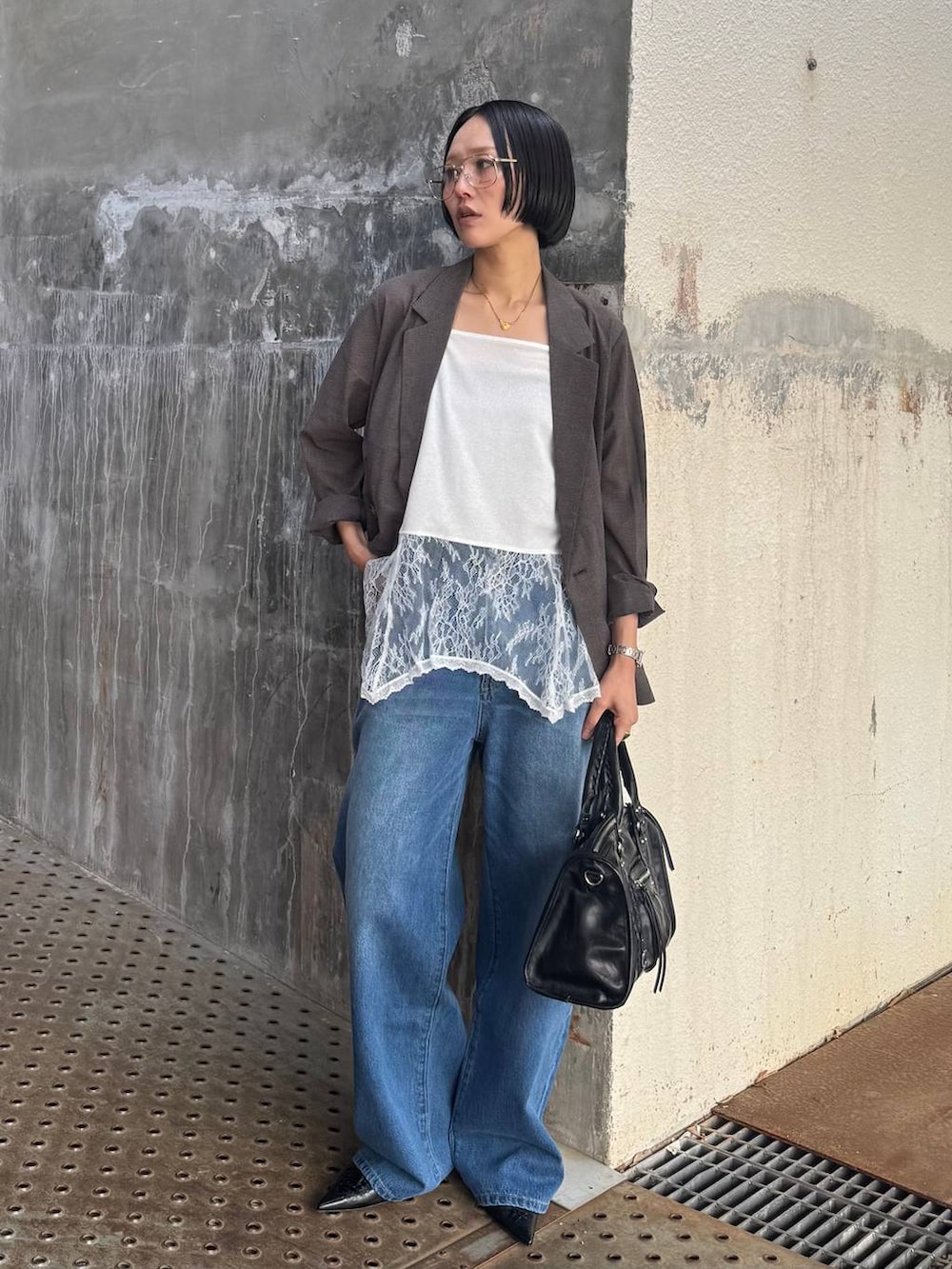 ブラック系のボストンバッグ、ブルー系のデニムパンツ、ブラウン系のテーラードジャケットを着用したレディースの春コーディネートの4枚目の写真