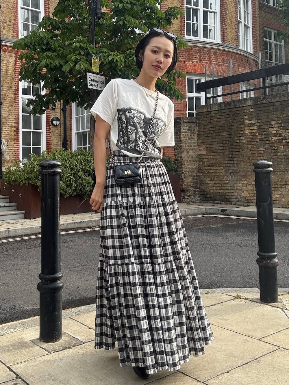 ブラック系のスカート、ホワイト系のTシャツ/カットソー、ブラック系のサングラスを着用したレディースの夏コーディネートの3枚目の写真