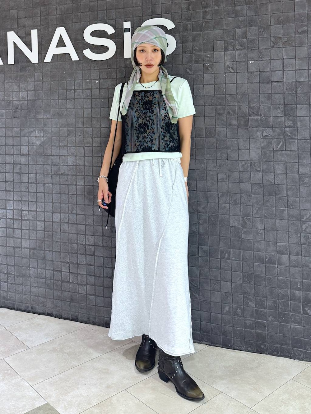グレー系のスカート、ブラック系のブーツ、グリーン系のTシャツ/カットソーを着用したレディースの夏コーディネートの2枚目の写真