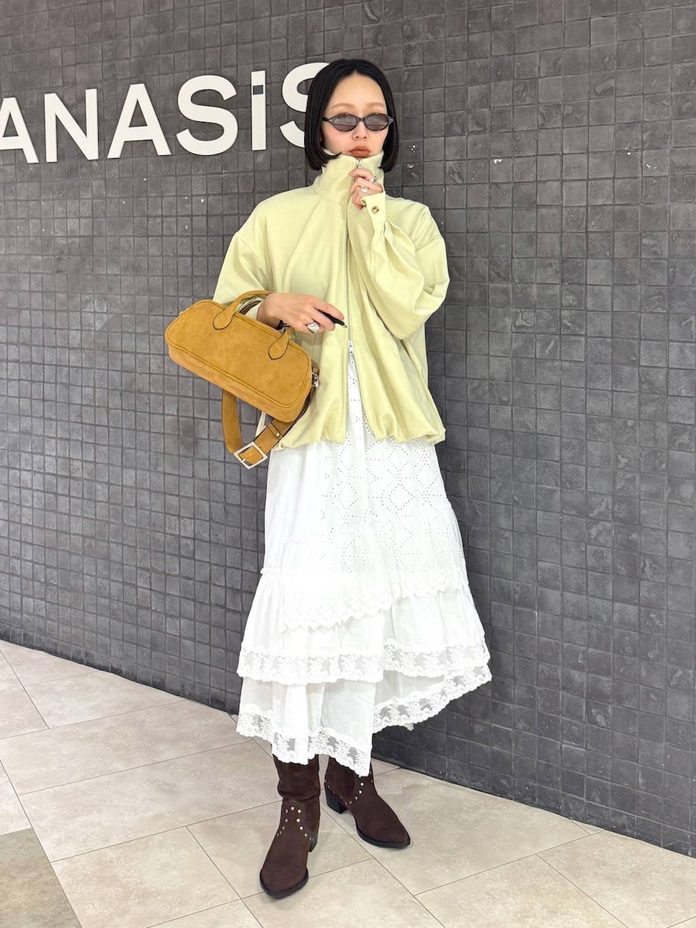 ブラウン系のボストンバッグ、ブラウン系のブーツ、ホワイト系のスカートを着用したレディースの春コーディネートの5枚目の写真