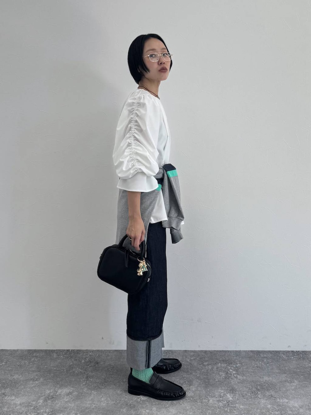 ブラック系のショルダーバッグ、ブルー系のデニムパンツを着用したレディースの冬コーディネートの4枚目の写真